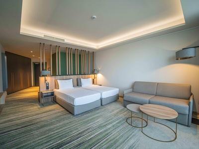 Modern hotelkamer met tweepersoonsbed, bank en stijlvolle tafels.