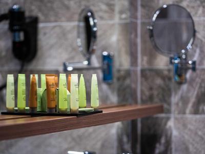 Hoteltoilettenartikelen op houten plank voor betegelde badkamerwand.