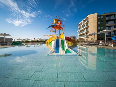 Kinderwaterslides in een groot ondiep zwembad voor een hotel bij helder weer.