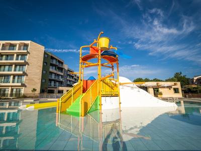 Kleurrijke waterspeeltuin met glijbanen in een hotelzwembad onder een blauwe lucht.