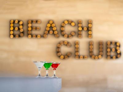 Kleurige cocktails voor een houten muur met de tekst BEACH CLUB van dennenappels.