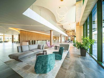 Moderne hotellobby met stijlvolle zitplaatsen en grote ramen met uitzicht op groen.