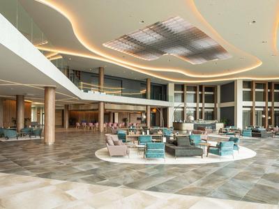 Grote hotel lobby met modern ontwerp en zithoeken.