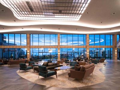 Ruime hotel lobby met moderne zitplaatsen en grote panoramische ramen.