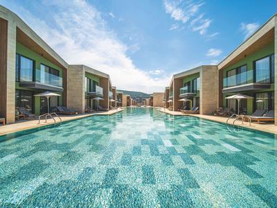 Modern buitenzwembad tussen twee rijen hotelkamers onder een heldere lucht.