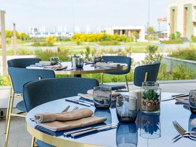Moderne buitenterras met stijlvolle tafels en stoelen in hotelrestaurant met uitzicht op groen.