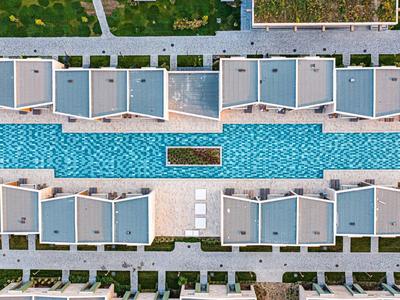 Luchtfoto van een langwerpig zwembad tussen rijen hotelbungalows.