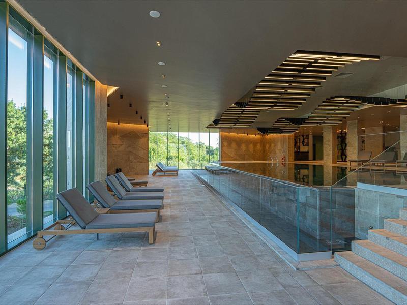 Moderne hotel lounge met grote ramen, lamellen en comfortabele stoelen.