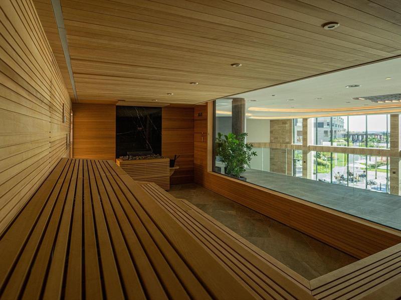 Interieur van een sauna met houten bekleding en groot raam met uitzicht naar buiten.