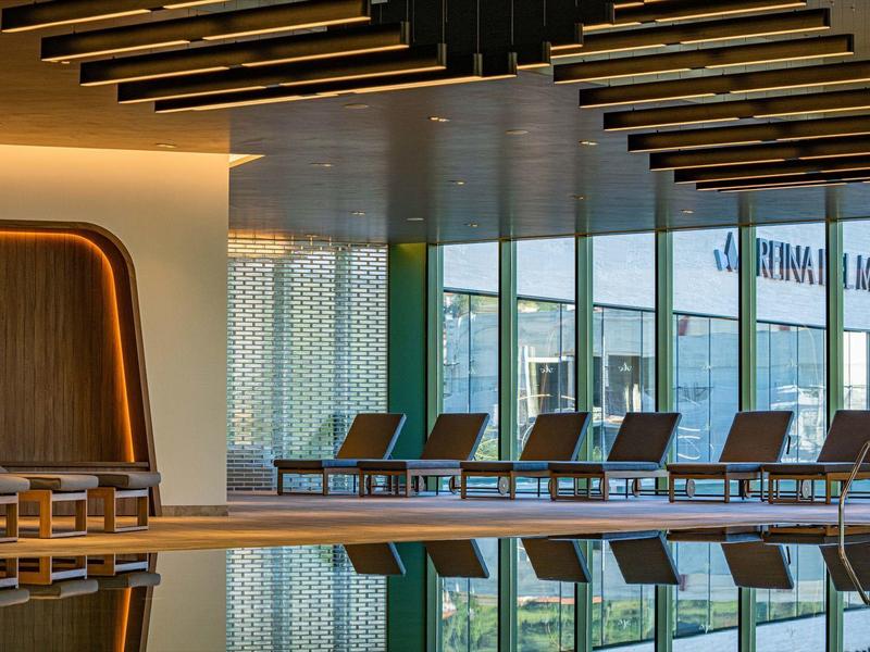 Moderne binnenzwembad met ligstoelen en warme verlichting in een hotel.