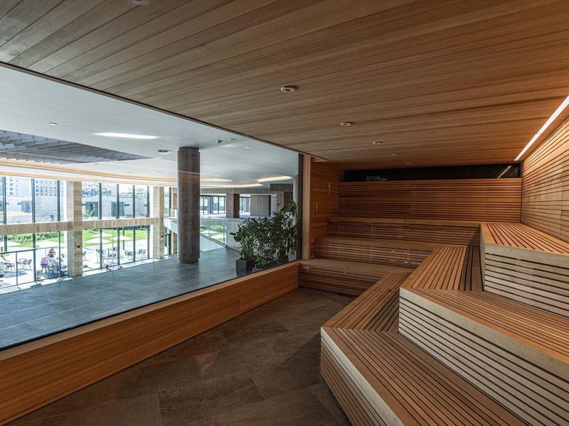 Moderne wellnessruimte met sauna en uitzicht op een binnenzwembad.