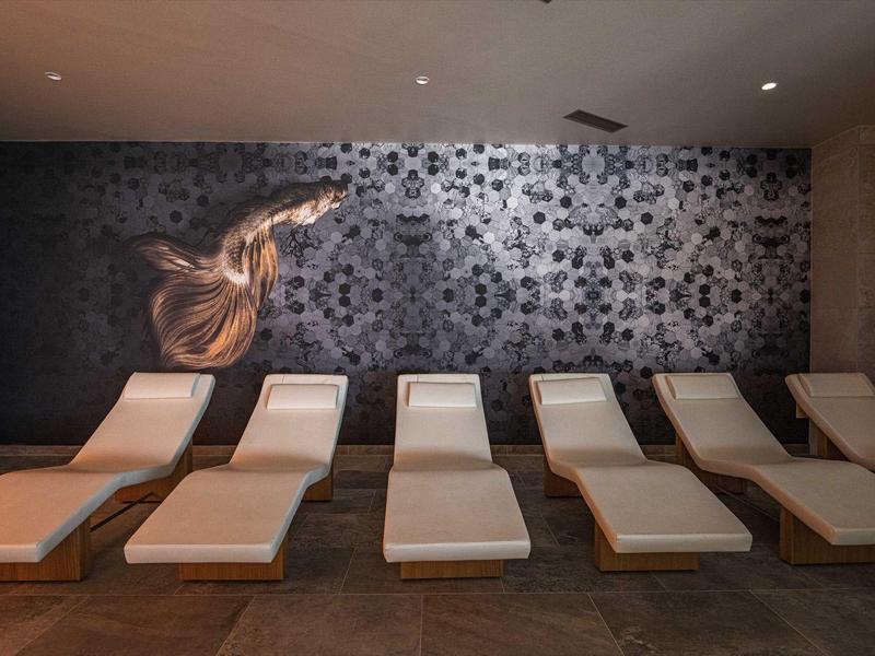 Rustruimte met zes beklede ligbedden voor een decoratieve muur in het spa-gedeelte.