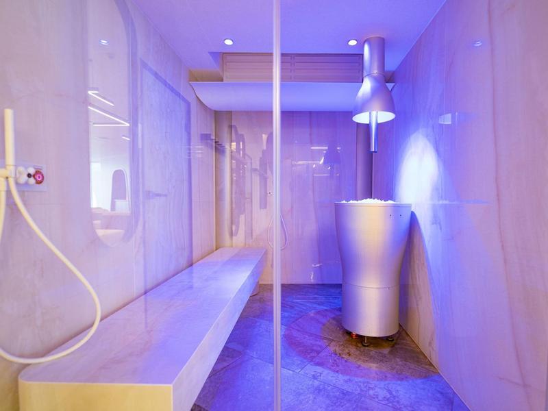 Moderne wellnessruimte met douche, houten bank en gekleurde verlichting