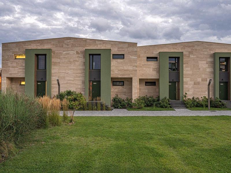 Moderne accommodatie met stenen rijtjeshuizen en een goed onderhouden gazon onder bewolkte lucht.
