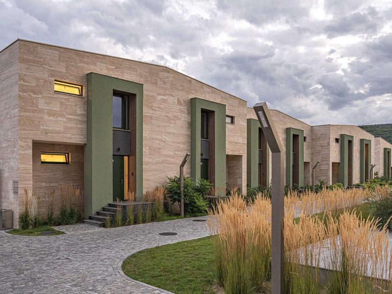 Rij van moderne gebouwen met beige gevels en grote ramen onder een bewolkte hemel.