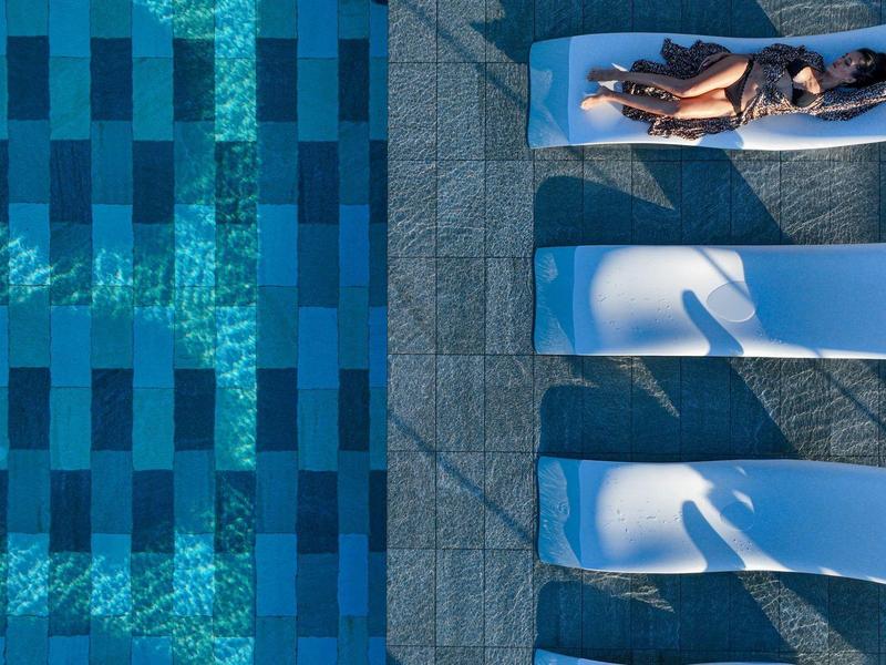 Bovenaanzicht van een zwembad met vier ligbedden en een schaduwrijke zone aan de zijkant.