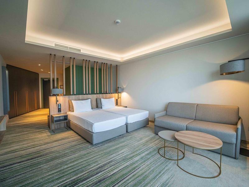 Modern hotelkamer met tweepersoonsbed, bank en stijlvolle tafels.