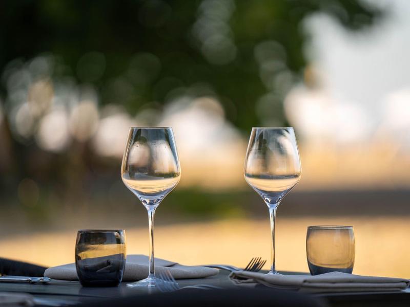 Lege wijnglazen en waterglazen op een gedekte buitentafel.