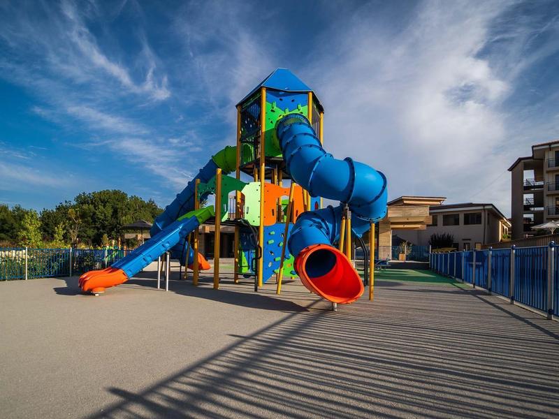 Kleurrijke speeltuin met glijbanen voor hotelgebouwen onder een blauwe lucht.