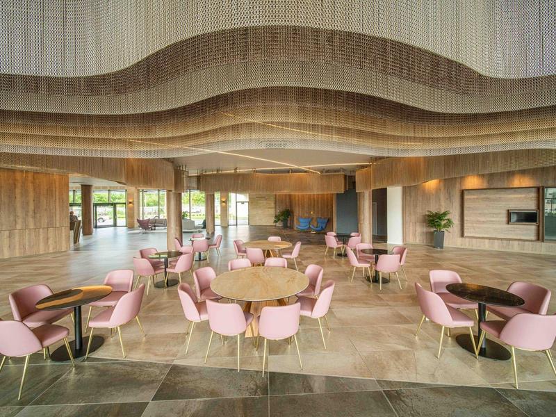 Moderne ontbijtruimte met roze stoelen en houten plafond.