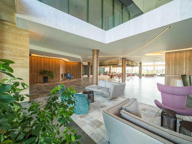 Lichte, moderne hotellobby met zithoeken en groene planten.