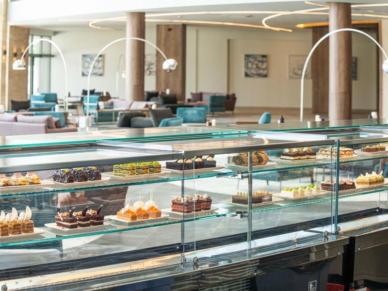 Moderne hotelbar met een vitrine met diverse taarten en gebakjes.