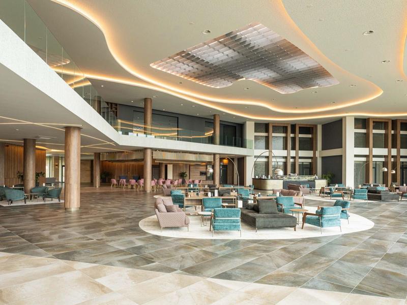 Grote hotel lobby met modern ontwerp en zithoeken.