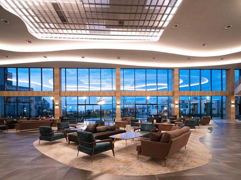 Ruime hotel lobby met moderne zitplaatsen en grote panoramische ramen.