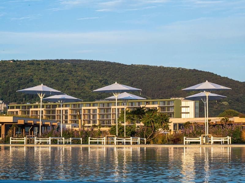 modern hotel met zwembad voor beboste heuvel onder blauwe lucht