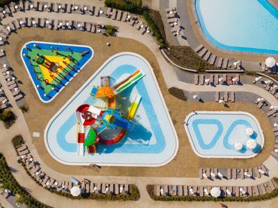 Luftaufnahme eines Wasserparks mit bunten Wasserrutschen und Liegestühlen neben einem großen Pool.