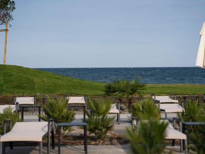 Chaises longues vides sur la plage avec vue sur la mer sous un ciel bleu.