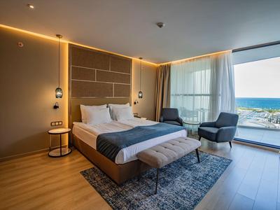 Modernes Hotelzimmer mit Doppelbett, Sitzgelegenheit und Balkon mit Meerblick