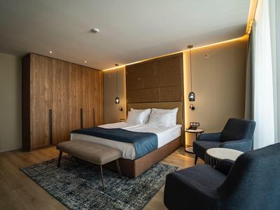 Modern eingerichtetes Hotelzimmer mit Doppelbett, Sitzbereich und großen Fenstern.