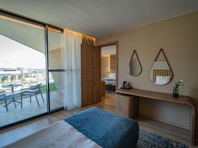 Modernes Hotelzimmer mit Balkon, Bett, Spiegeln und Kommode mit Blumendekoration.