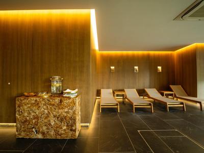 Moderne Entspannungszone mit Holzverkleidung, bequemen Liegestühlen und sanfter Beleuchtung.