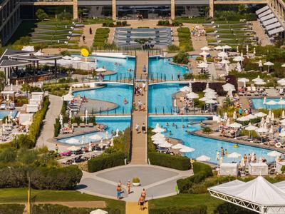 Großer Außenpool mit Brücken, Liegestühlen und Sonnenschirmen in einem Hotelresort