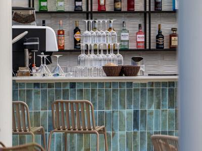 Moderner Hotelbarbereich mit türkisfliesen und leeren Stühlen vor der Bar