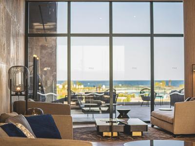 Hall d'hôtel moderne avec fauteuils en cuir et grande fenêtre donnant sur la mer.