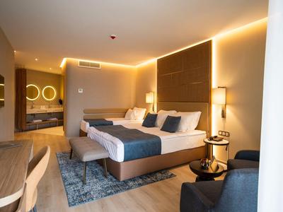 Modern eingerichtetes Hotelzimmer mit Doppelbett, indirekter Beleuchtung und Sitzbereich.