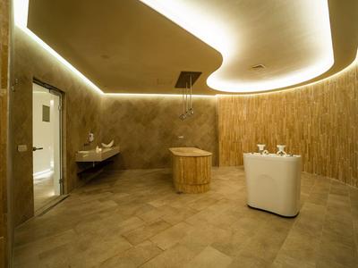 Moderner Wellnessraum mit Holzbadewanne und stimmungsvoller indirekter Beleuchtung.