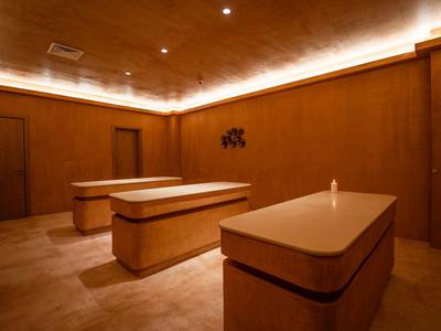 Dunkler Entspannungsraum mit drei Liegen und indirekter Deckenbeleuchtung.