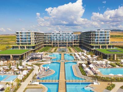 Moderner Hotelkomplex mit großen Pools und Liegestühlen in einer weiten Landschaft unter blauem Himmel.