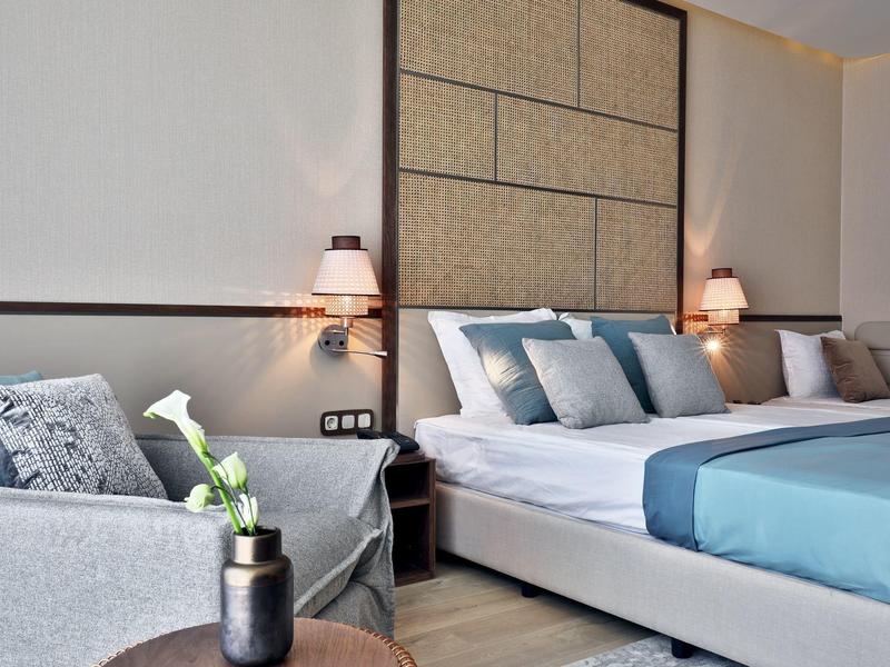 Modernes Hotelzimmer mit einem großen, bequemen Bett und einem Sitzbereich mit Sofa.