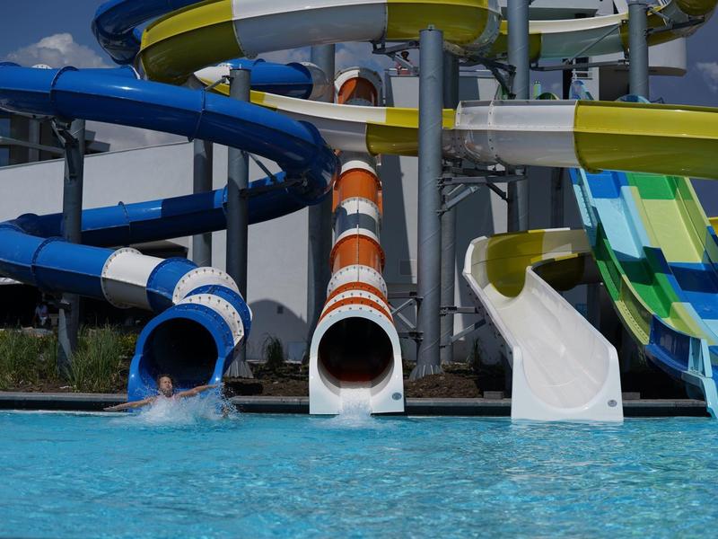 Mehrere bunte Wasserrutschen führen in einen Pool in einem Wasserpark.