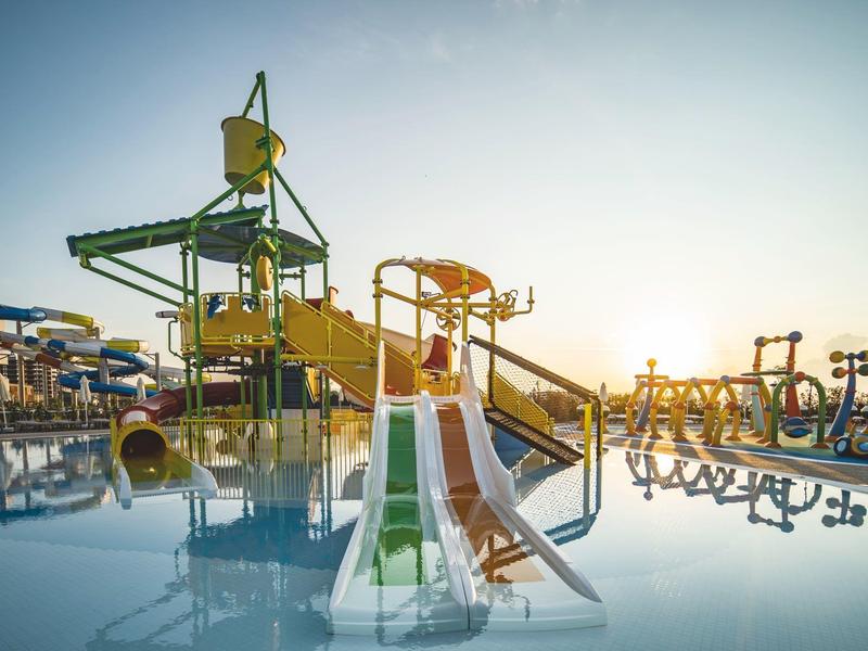 Kinder-Wasserspielplatz mit bunten Rutschen und Wasserattraktionen bei Sonnenuntergang.