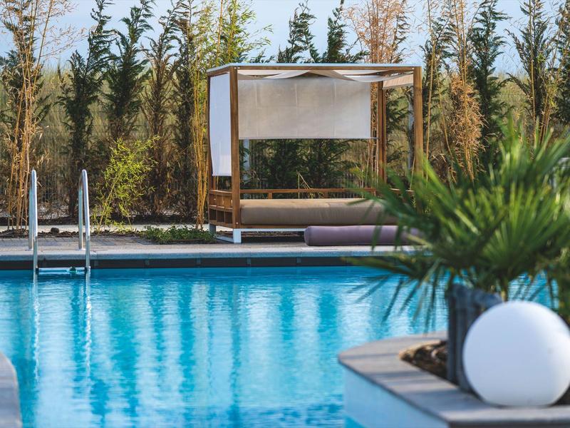 Moderner Außenpool mit Liege und grünem Pflanzenhintergrund an einem sonnigen Tag