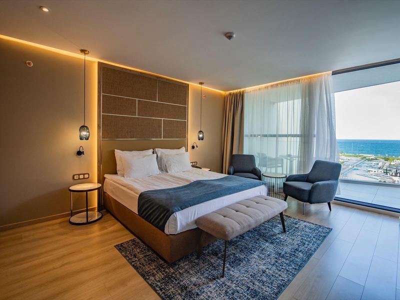 Modernes Hotelzimmer mit Doppelbett, Sitzgelegenheit und Balkon mit Meerblick
