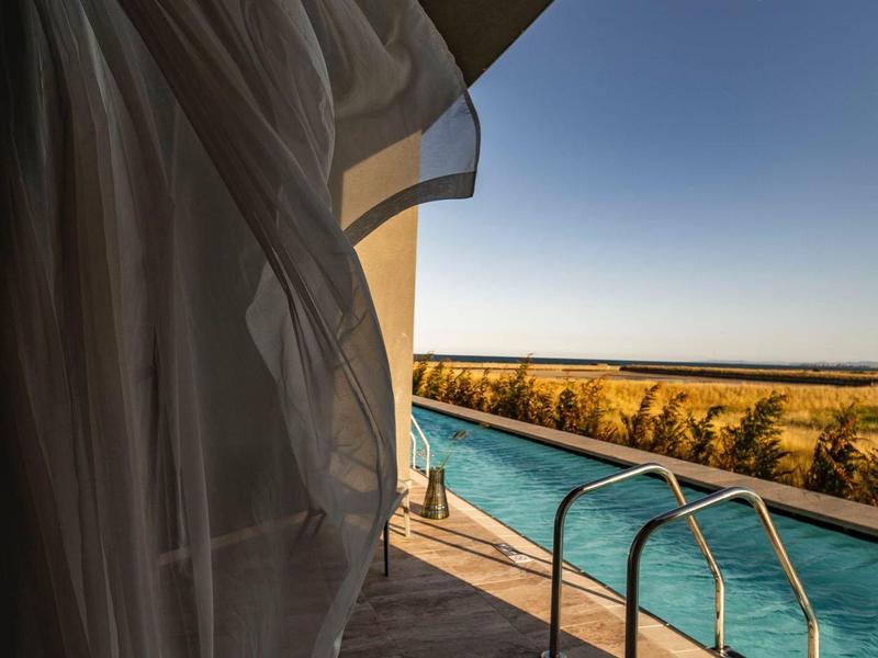 Schwimmbad mit Poolleiter neben einem Vorhang, mit Blick auf die Landschaft bei Sonnenuntergang.