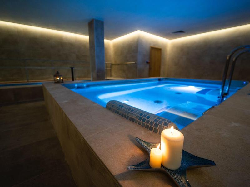 Entspannendes beleuchtetes Whirlpool-Bad mit Kerzen in einem ruhigen Innenraum.