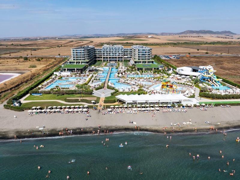Luxuriöses Hotel mit mehreren Pools an einem Strand in einer trockenen, weiten Umgebung.